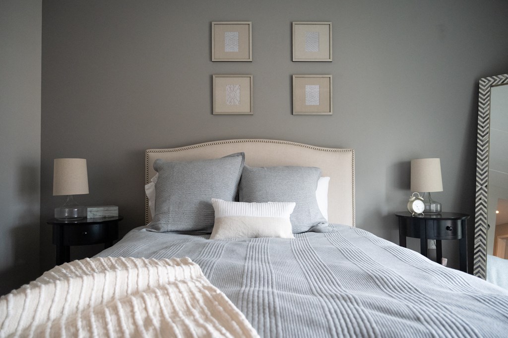 a bedroom with grey walls and a bed with a striped comforter