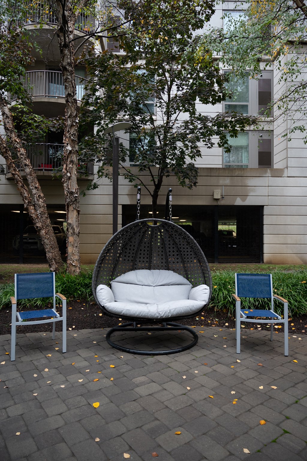 a large white egg shaped chair with a white pillow on top of it between two blue chairs