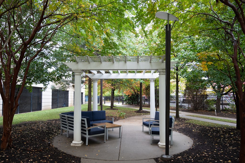 a pergola with couches and chairs in a park