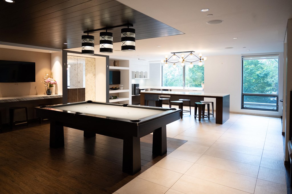 a pool table in a living room with a kitchen in the background