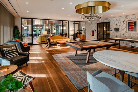 A modern living room with a pool table and a large chandelier.