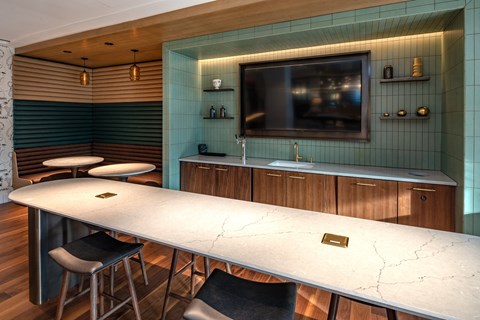 A modern kitchen with a long white table and black chairs.