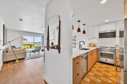 A modern kitchen with wooden floors and stainless steel appliances.