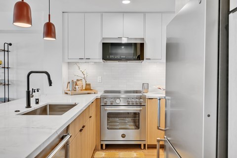 A modern kitchen with a stainless steel refrigerator, a double oven, and a microwave above the stove.