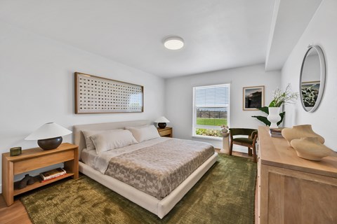 A bedroom with a bed, nightstand, and a window with blinds.