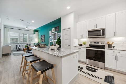 a kitchen with white cabinets and a large island with bar stools