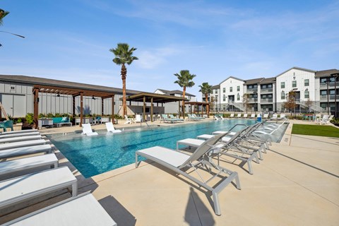 a swimming pool with lounge chairs at the resort on a sunny day