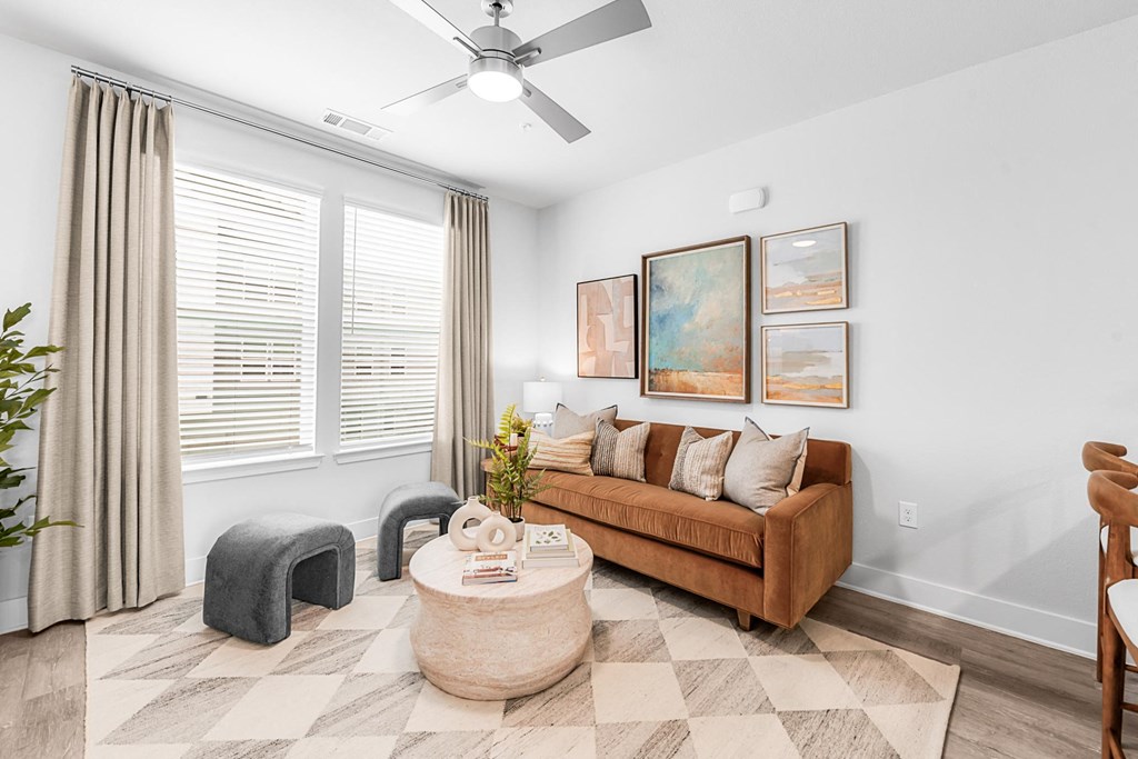 A living room with a brown couch, a round coffee table, and a ceiling fan.