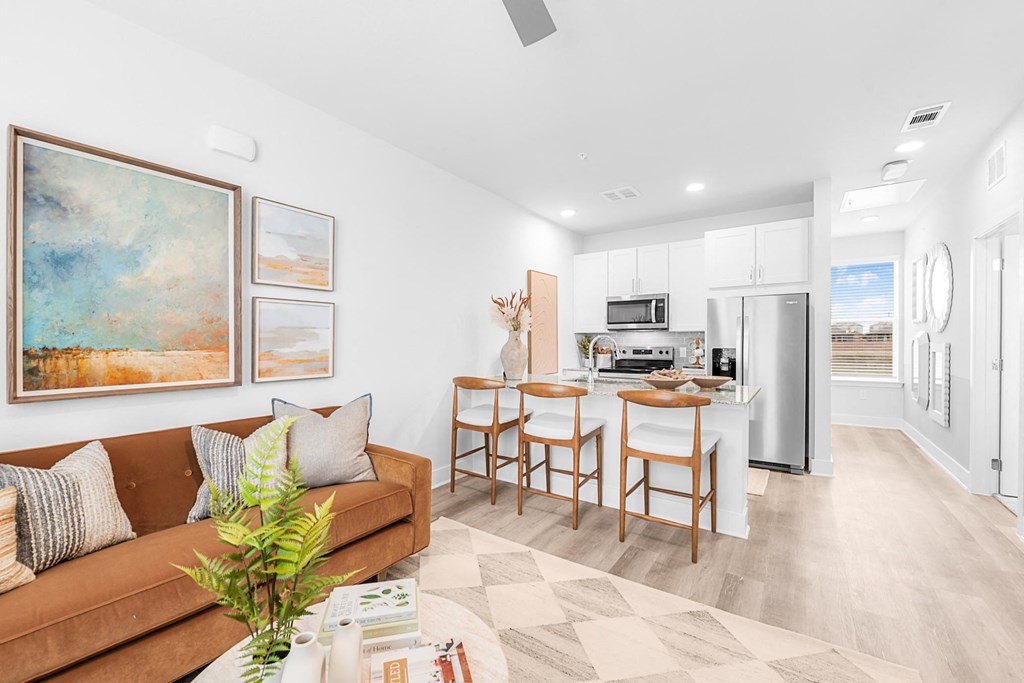 A living room with a brown couch and a painting on the wall.