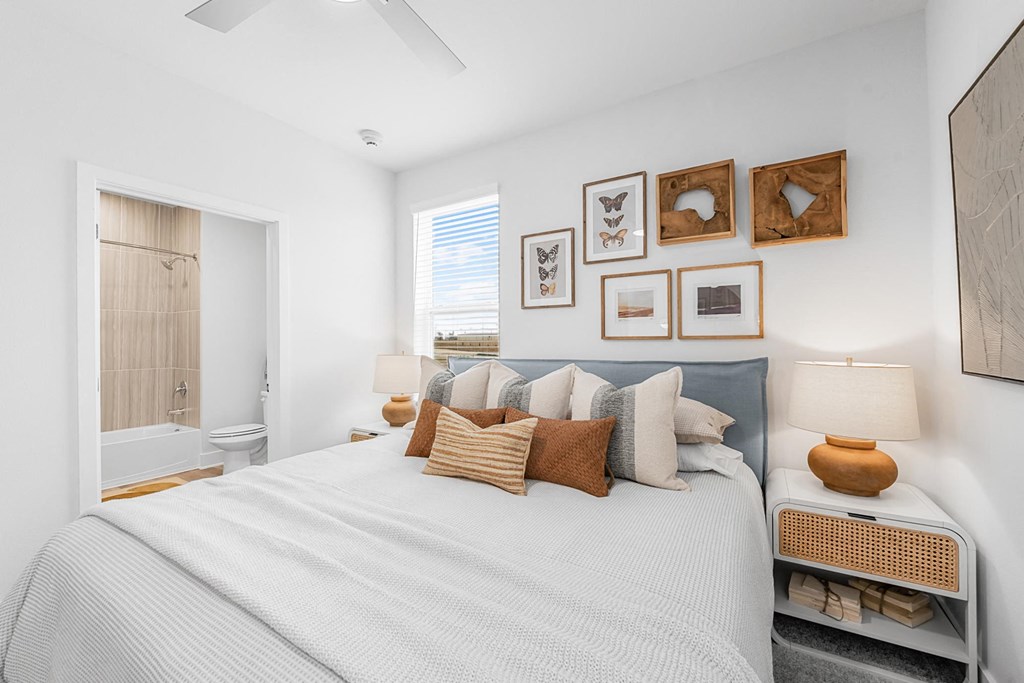 A bedroom with a bed, pillows, and pictures on the wall.