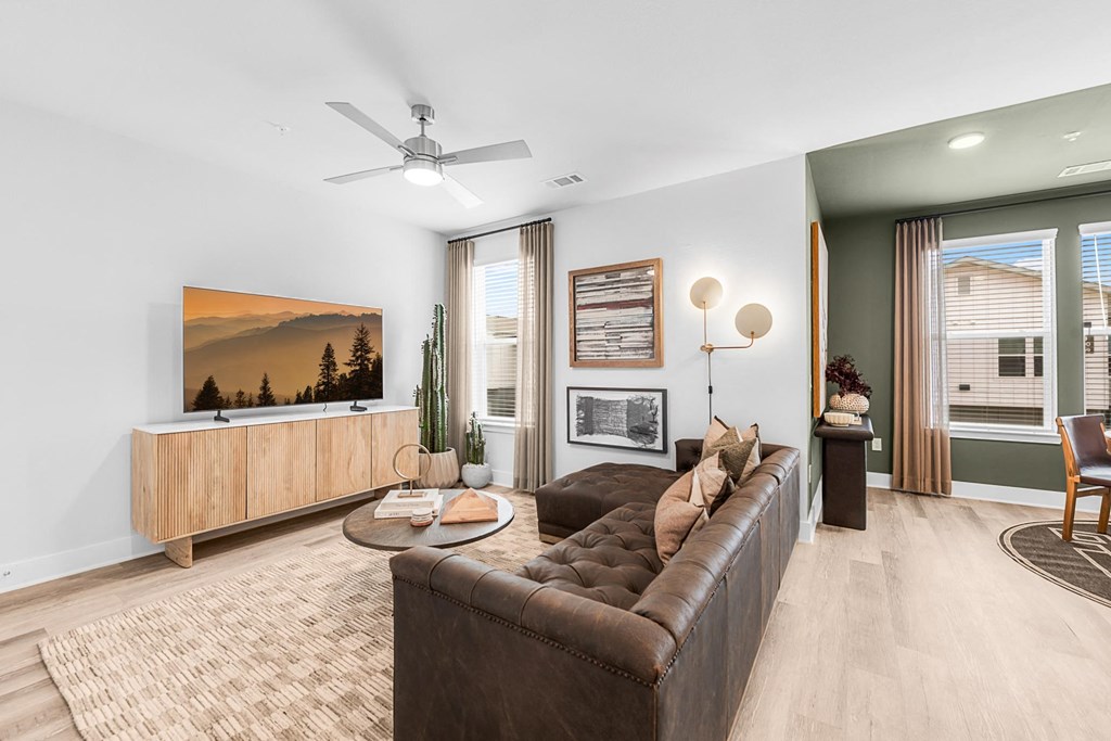 A living room with a brown couch and a painting of a mountain scene on the wall.