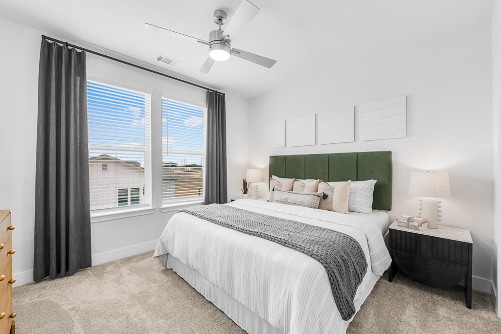 A bedroom with a large bed and a ceiling fan.