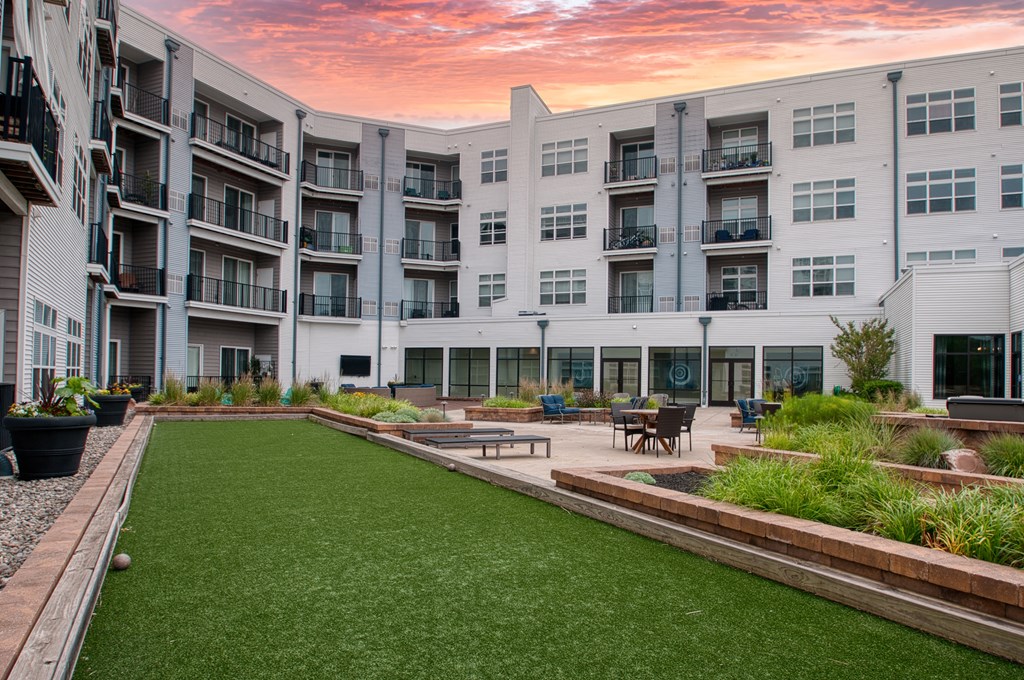 a courtyard with a grassy area and a white building in the background