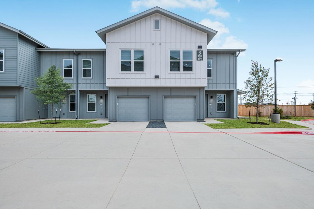 A modern two-story house with a garage and a driveway in front.