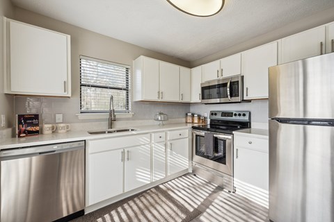 A modern kitchen with white cabinets and stainless steel appliances.