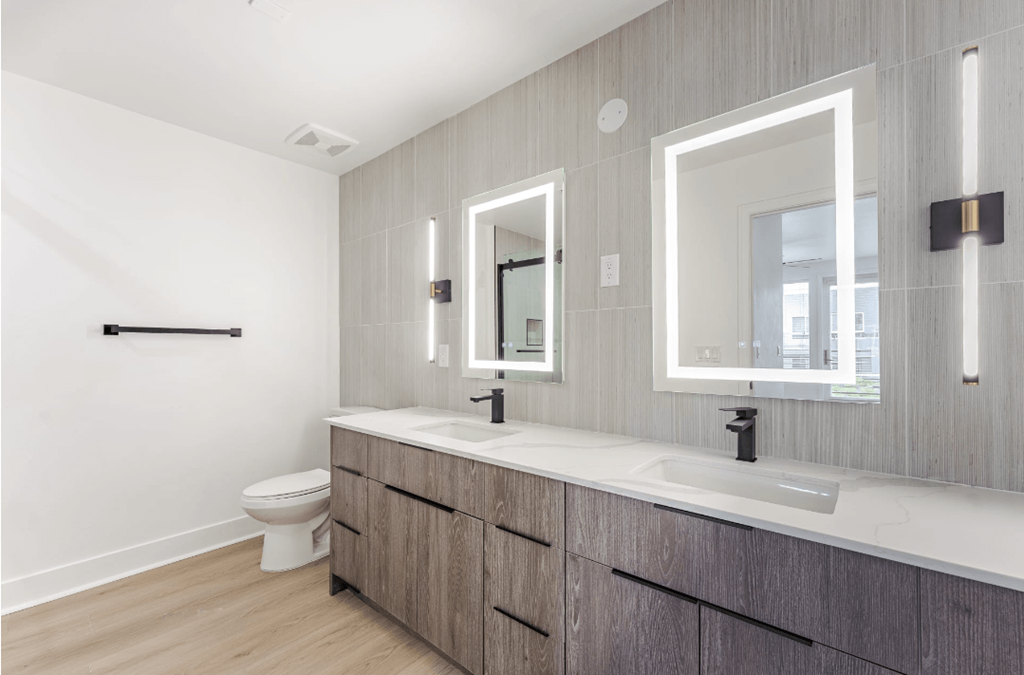 A bathroom with a toilet, sink, and mirror.