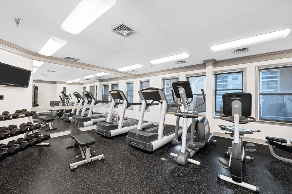 a gym with cardio equipment and weights on the floor