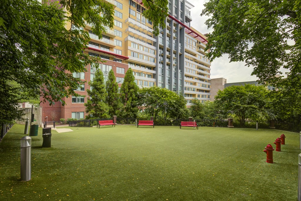 a park with green grass and red benches in front of an apartment building