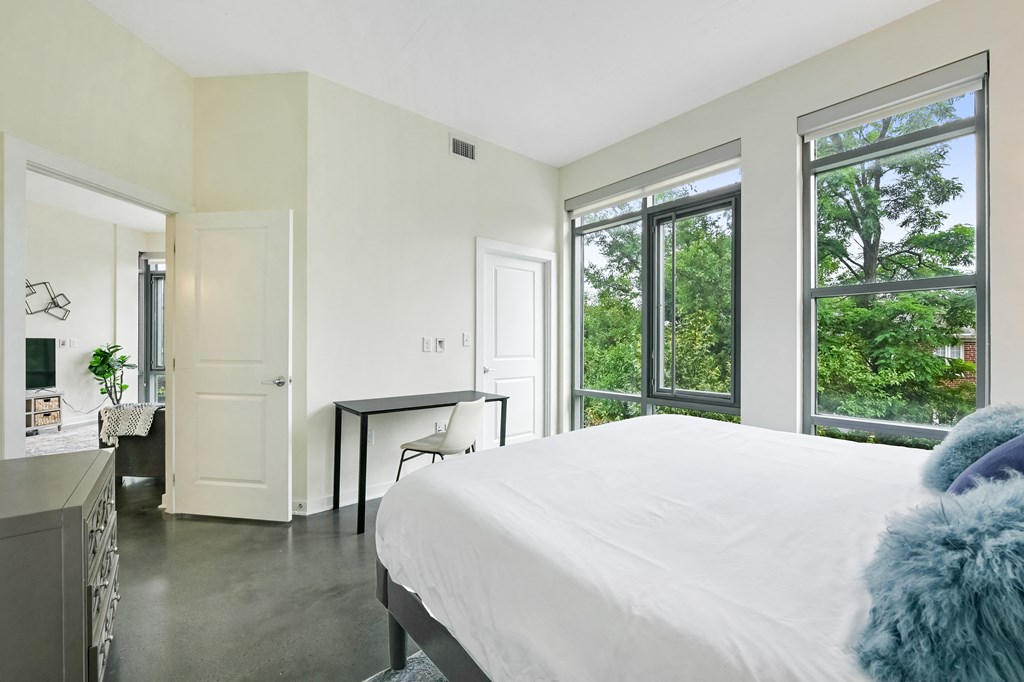a bedroom with a white bed and large windows