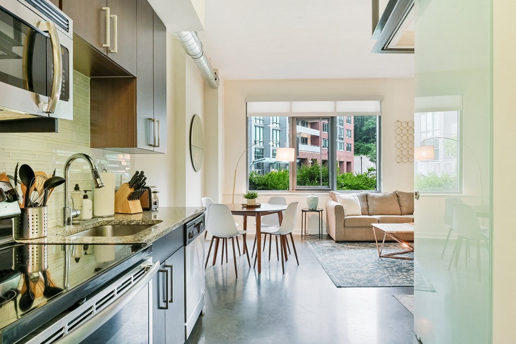 a kitchen and living room with a large window and a table with chairs