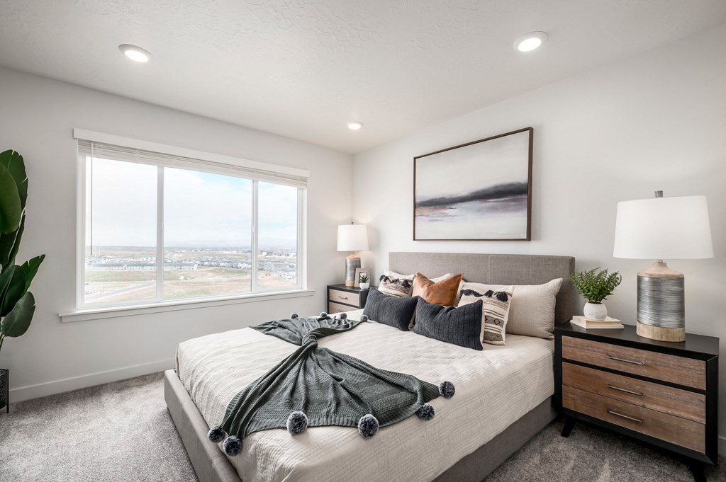 a bedroom with a large window and a bed with blankets and pillows