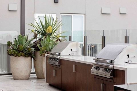 A modern outdoor kitchen with a grill and potted plants.