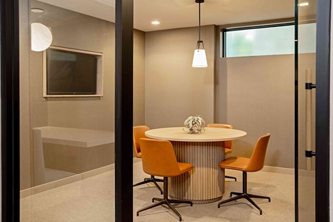 A modern dining room with a round table and orange chairs.