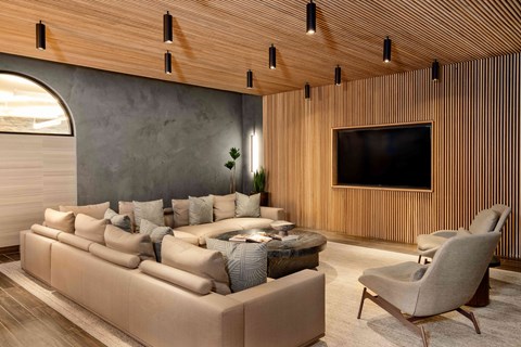 A modern living room with a large couch and a flat screen TV mounted on the wall.