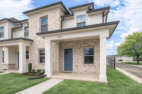 A two-story house with a front yard and a black gate.