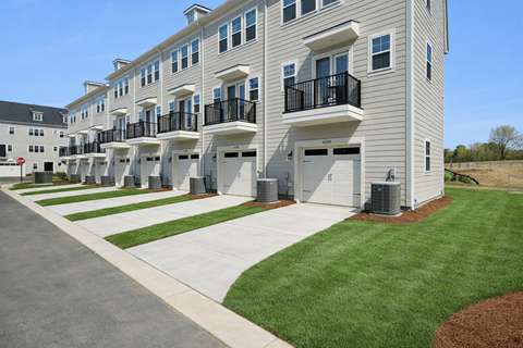 Apartment complex with white buildings and green grass.