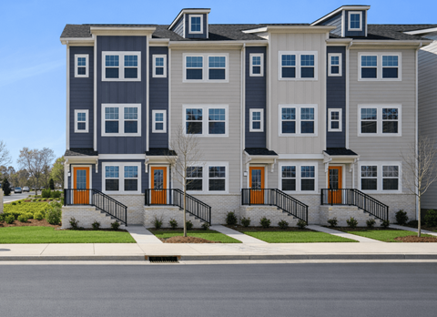 A modern two-story apartment building with grey and white exterior and orange doors.