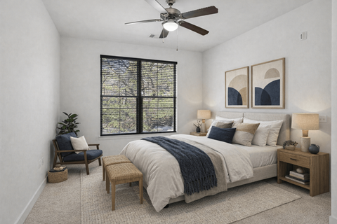 A bedroom with a large bed, a ceiling fan, and a window with blinds.