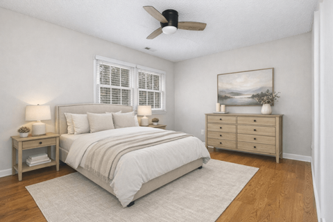A bedroom with a bed, nightstand, and a painting on the wall.