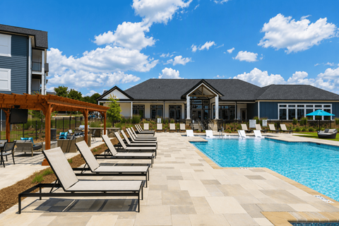 A pool area with sun loungers and a building in the background.