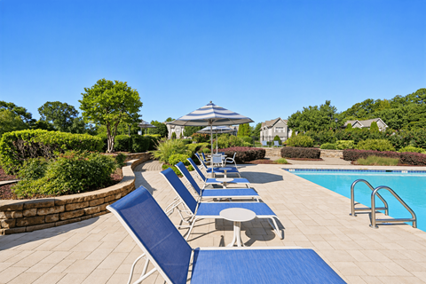 A pool with sun loungers and a gazebo in the background.