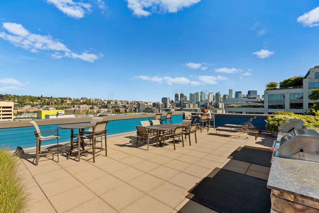 an outdoor terrace with tables and chairs with a city skyline in the background  at Dexter Lake Union, Seattle, WA, 98109