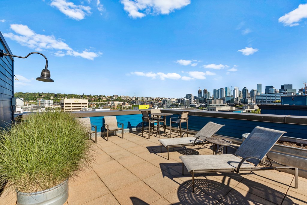 a roof deck with lounge chairs and a table with a view of the city  at Dexter Lake Union, Seattle, Washington