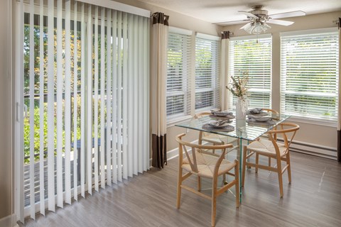 a dining room with white blinds and a table and chairs