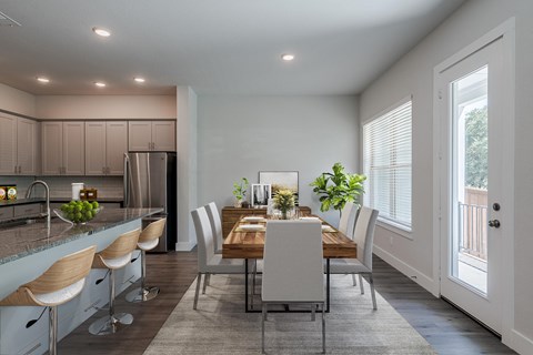 a dining room with a wooden table and chairs and a kitchen with a large window