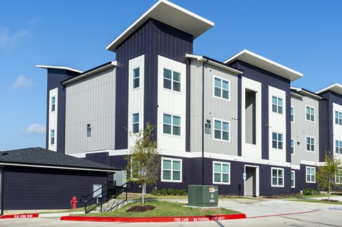 A modern apartment building with a garage door and a fire hydrant in front.