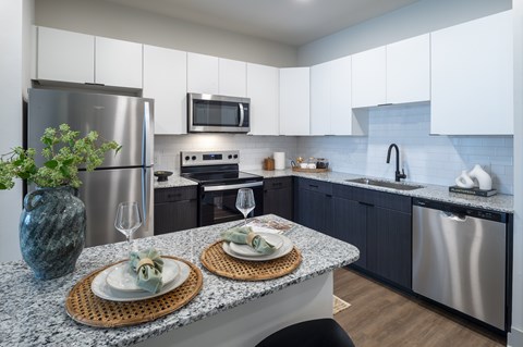 A modern kitchen with a granite countertop and stainless steel appliances.