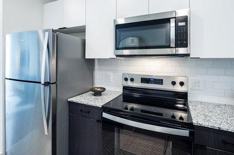 A modern kitchen with a stainless steel refrigerator, microwave, and stove.