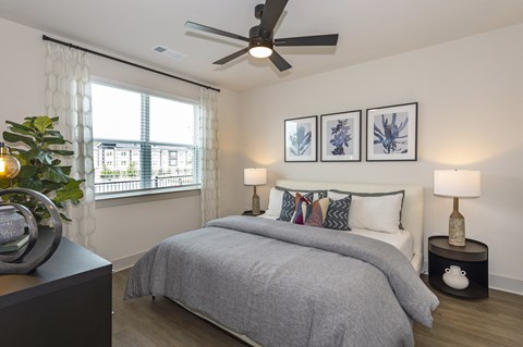 A bedroom with a bed, two lamps, and a ceiling fan.