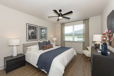 A bedroom with a bed, a chair, and a ceiling fan.