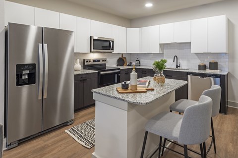 A modern kitchen with a granite countertop and stainless steel appliances.