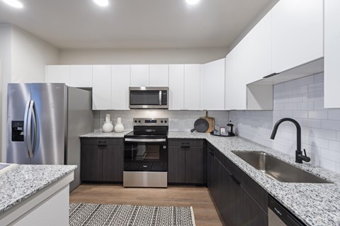 A modern kitchen with a stainless steel refrigerator and a microwave above the oven.