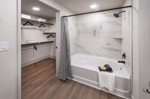 A bathroom with a marble wall and a bathtub with a towel on it.