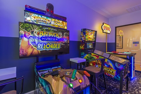 A room with a TV showing a game called Big Buck Hunter and a game machine in front of it.