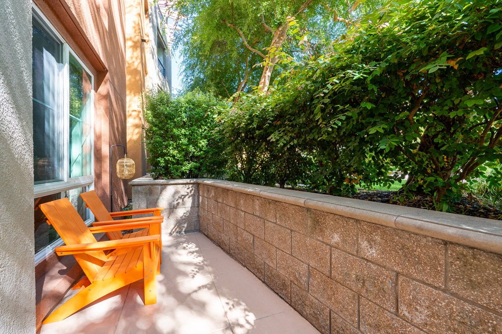 a small patio with orange chairs and a brick wall