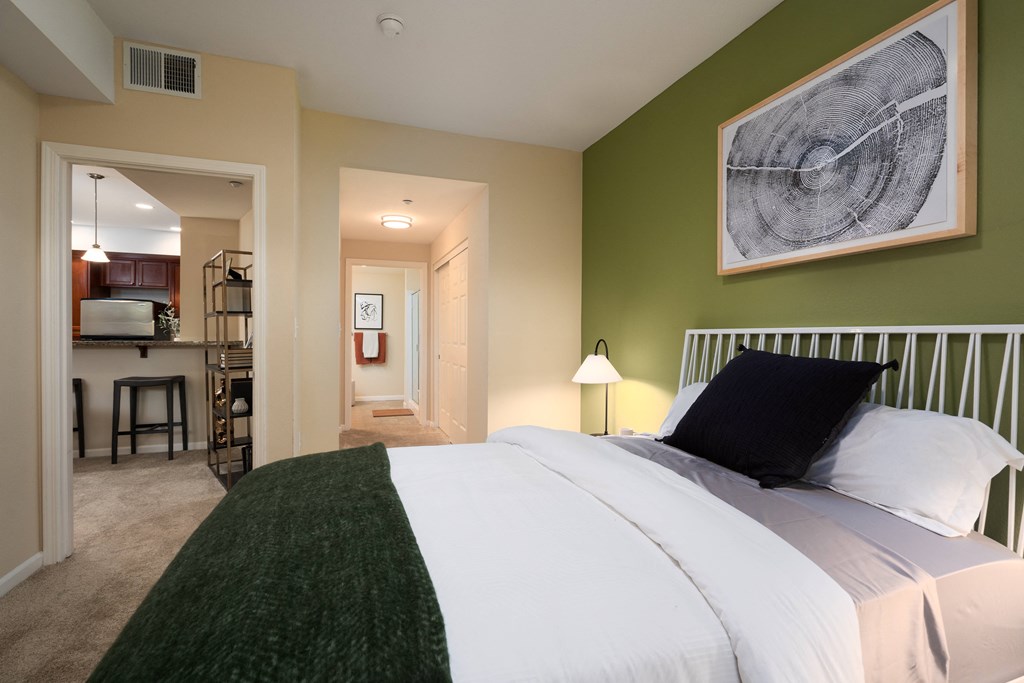 a bedroom with a bed and a view of the kitchen and living room